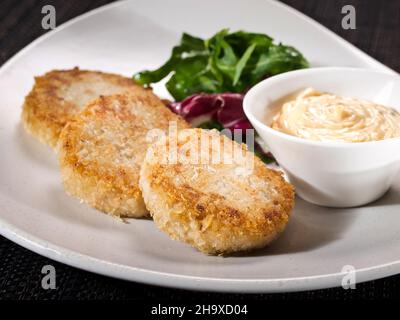 portion de patties de poulet sur une assiette servie avec un mélange de salade et une sauce mille île, photo sur fond sombre Banque D'Images