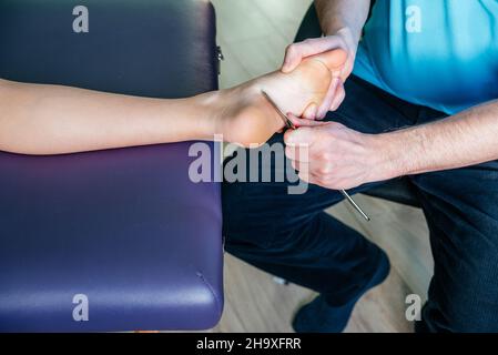 Physiothérapeute fixant la douleur plantaire au talon avec l'outil IASTM guasha Banque D'Images