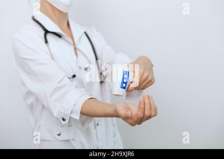 Pistolet de mesure de température dans les mains du médecin.Gros plan d'un médecin portant un masque chirurgical de protection prêt à l'emploi thermomètre infrarouge isométrique Banque D'Images