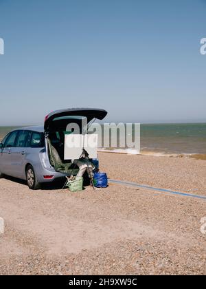 Un artiste peint depuis le coffre de sa voiture avec un chevalet et une toile sur la côte estivale de la mer du Royaume-Uni - plein air peinture - en plein air Banque D'Images