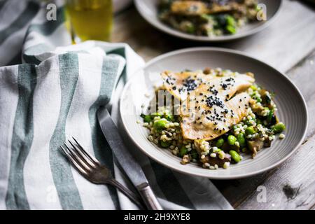 Filet de poisson grillé avec risotto aux champignons et haricots édamames sur une surface rustique Banque D'Images