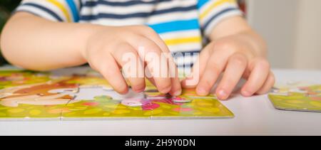 Les mains de l'enfant rapprochent ensemble une photo de puzzles Banque D'Images