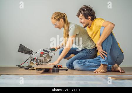 Couple marié installant un nouveau parquet stratifié en bois sur un plancher de film chaud.Système de chauffage au sol infrarouge sous sol stratifié Banque D'Images