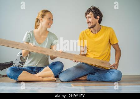 Couple marié installant un nouveau parquet stratifié en bois sur un plancher de film chaud.Système de chauffage au sol infrarouge sous sol stratifié Banque D'Images