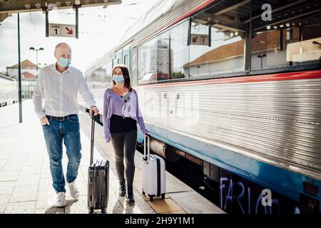 Touristes avec des valises et des masques marchant sur la plate-forme à côté du train, Portugal Banque D'Images