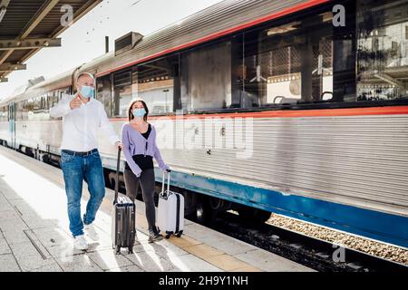 Touristes avec des valises et des masques sur la plate-forme à côté du train, Portugal Banque D'Images