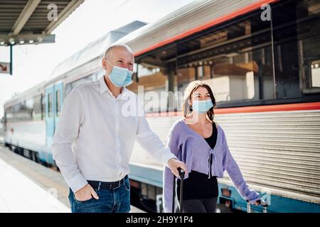 Touristes avec des valises et des masques sur la plate-forme à côté du train, Portugal Banque D'Images