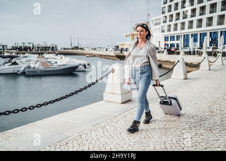 Jeune femme avec valise à pied en milieu urbain, Faro, Portugal Banque D'Images