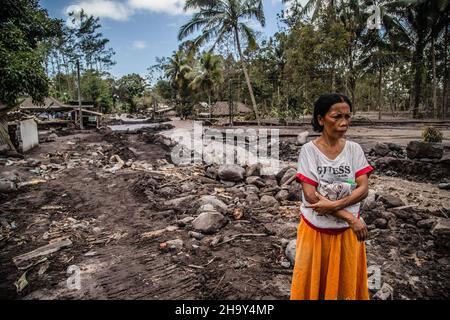 Kamar Kajang, Indonésie.09th décembre 2021.Une femme regarde sa maison qui a été enterrée par des cendres volcaniques à Kamar Kajang, Lumajang.Au moins 14 personnes sont mortes et des dizaines sont blessées après que le mont Semeru, un volcan de la province de Java est en Indonésie, a éclaté samedi, lançant des tours de cendres et des nuages chauds qui couvraient les villages voisins.Crédit : SOPA Images Limited/Alamy Live News Banque D'Images