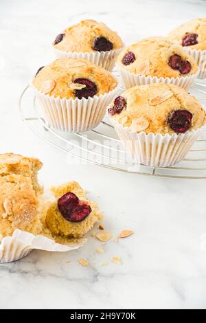Gros plan d'un muffin à la cerise fait maison au premier plan avec des muffins sur la grille de refroidissement en arrière-plan.Vue à angle bas. Banque D'Images