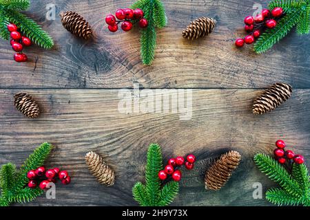 Cadre de Noël avec branches de sapin et baies rouges comme décoration sur bois brun foncé avec espace de copie.Vue de dessus. Banque D'Images