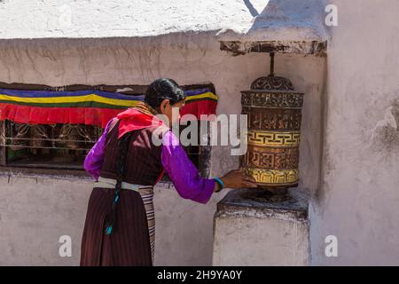 Une réfugiée tibétaine tournant une roue de prière à la base de la Boudhanath Stupa, Katmandou, Népal. Banque D'Images
