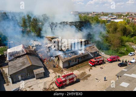 Vue aérienne des pompiers l'extinction a ruiné le bâtiment sur le feu avec le toit écrasé et la montée de fumée sombre. Banque D'Images