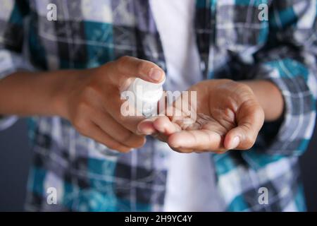 gros plan de la main d'un jeune homme à l'aide d'un spray désinfectant pour les mains. Banque D'Images