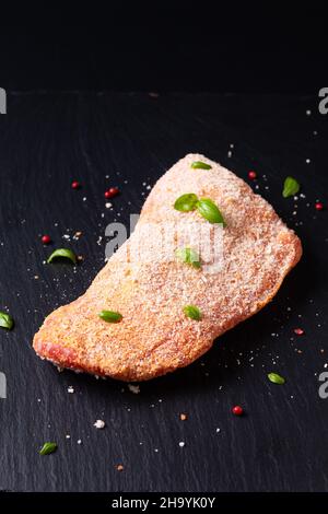 Concept alimentaire veau cordon bleu non cuit sur panneau en pierre d'ardoise noire avec espace de copie Banque D'Images