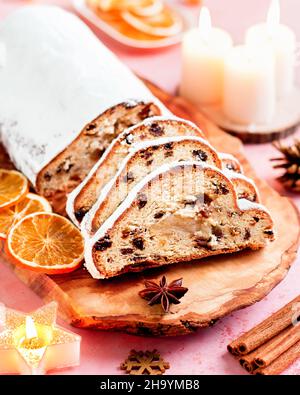 Arrière-plan avec gâteau de Noël Stollen et décor doré sur table rose.Vue de dessus de Christmas Stollen, bougies allumées, gâteau de Noël et boules dorées Banque D'Images