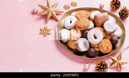 Les délices des fêtes polvorones et les mantecados bordent en plaque dorée sur une table rose décorée de boules dorées et de cônes de pin, bannière web, espace copie Banque D'Images