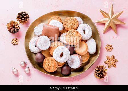 Spécialités de vacances polvorones et mantecados en assiette dorée sur table rose décorée de boules dorées et de cônes de pin, vue de dessus Banque D'Images