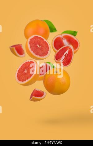 Pamplemousse frais tranché sur fond jaune.Concept de fruit minimal.Vitamines, concept de régime sain.Pamplemousse entier et en tranches flottant dans l'air. Banque D'Images