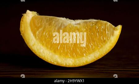 Fruit frais juteux Orange segments sur fond noir.Une tranche d'orange fraîche et juteuse repose sur la table sur un fond noir, le concept de pr Banque D'Images