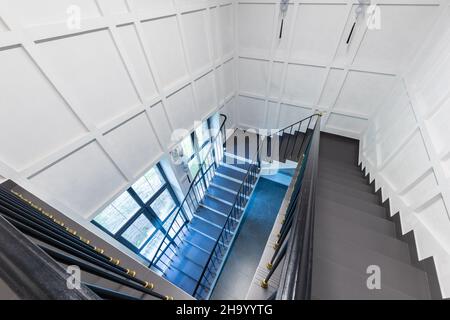 vue de dessus de l'escalier, dont les marches sont en pierre naturelle, marbre et granit, murs blancs et une grande fenêtre Banque D'Images