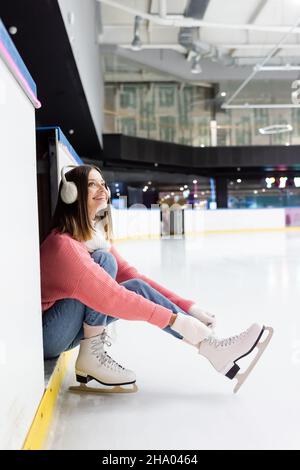 jeune femme gaie nouant des lacets de chaussures sur des patins à glace Banque D'Images