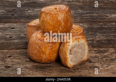 Photo de studio de petits tourtes de porc reposant sur une planche en bois sombre - John Gollop Banque D'Images