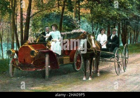 CHANGER LES TEMPS - Une carte postale d'environ 1910 présentant un jeune couple démontrant à leurs amis la forme des choses à venir.j avec leur nouveau voiture à moteur debout à côté de la calèche de leur voisin Banque D'Images