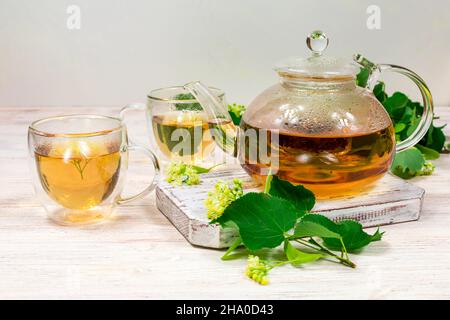 Théière et deux tasses de thé avec un tilleul sur une table en bois. Thé de guérison. Banque D'Images