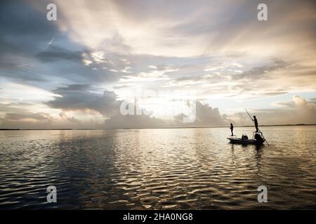 Une femme pêche à la mouche à partir d'un bateau dans les clés de floride au coucher du soleil Banque D'Images