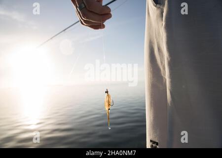 Un gros plan d'un pêcheur tenant une ligne de pêche avec une lure goutte à goutte Banque D'Images