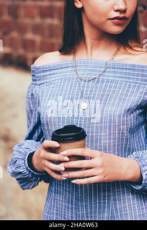 Une femme dans une combinaison rayée posant avec une tasse de café Banque D'Images