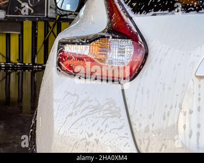 Bulles de savon circulant sur la voiture lavée avec de la mousse Banque D'Images