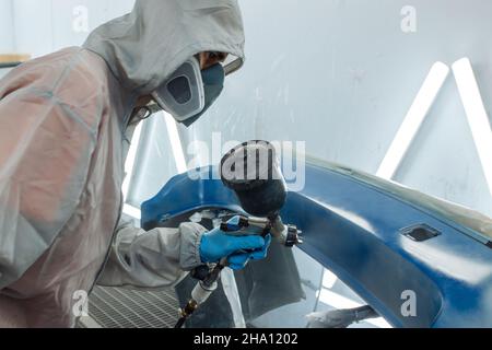 Un peintre automobile professionnel peint dans un garage par aérographe. Banque D'Images