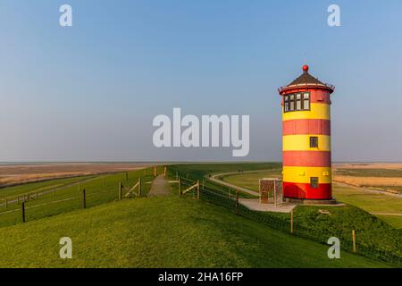 Le phare rayé rouge et jaune de Pilsum sur les rives de la mer des Wadden en Allemagne Banque D'Images