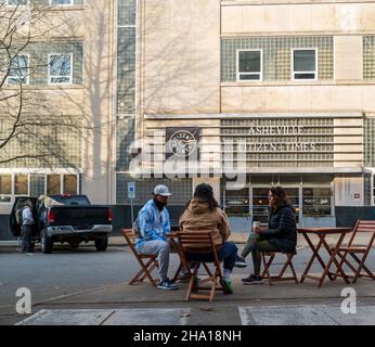 Asheville, Caroline du Nord, États-Unis -- 6 décembre 2021.Photo de trois amis prenant un café le matin à une table extérieure à Asheville, en Caroline du Nord. Banque D'Images