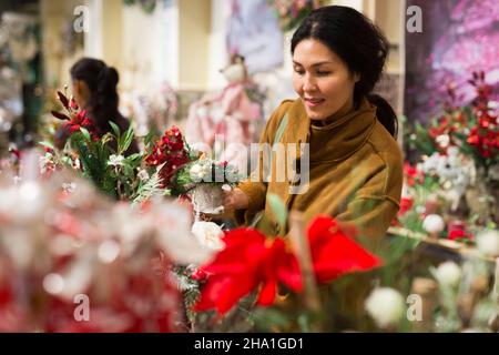 Une femme asiatique positive choisit une composition de Noël Banque D'Images