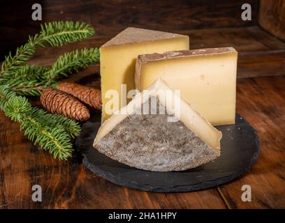 Collection de fromages, fromages de vache française comte, beaufort, abondance, tomme de savoie et cônes de sapin Banque D'Images