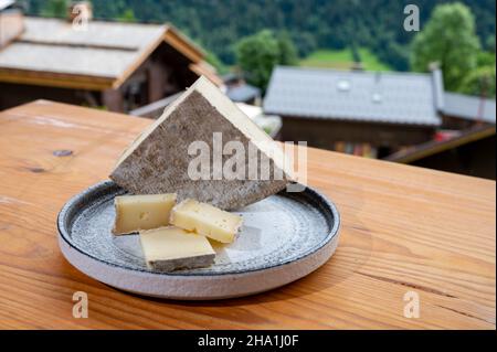 Collection de fromages, tomme de savoie et village de montagnes françaises en haute-Savoie en été en arrière-plan Banque D'Images