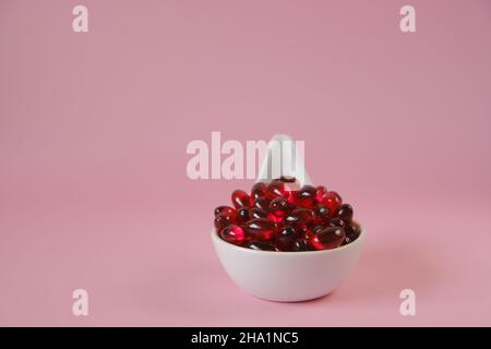 Capsules d'huile de krill dans une cuillère en céramique sur fond rose.Suppléments naturels et vitamine.acides gras oméga.alimentation saine et suppléments alimentaires Banque D'Images