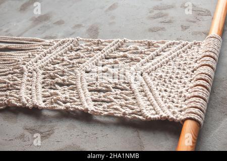Tissage à partir de fils de coton travail décoratif à partir de 100% coton dans le style de macrame, fait à la main sur un fond de béton.Passe-temps pour femmes. Banque D'Images