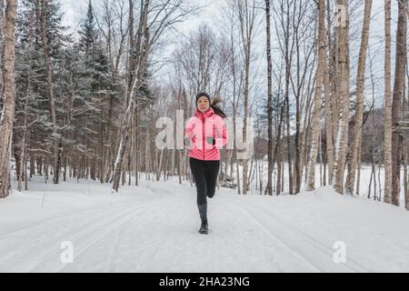 Femme d'hiver qui court dans la neige.Un coureur s'est sorti en hiver dans la forêt.S'adapte à un style de vie sain de beau jeune modèle sportif Banque D'Images