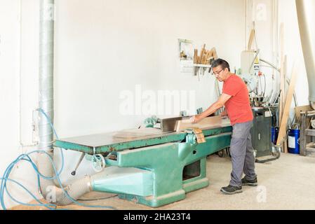 Homme adulte travaillant manuellement avec une machine de rabotage du bois Banque D'Images