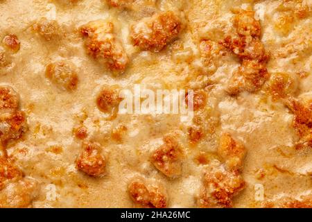 Gros plan de fromage fondu bruni avec morceaux de filet de poulet frits sur la pizza Banque D'Images