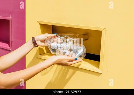 Une femme heureuse trie les déchets et jette des bouteilles en plastique propres dans un récipient de recyclage.Sauvez la planète ! Banque D'Images