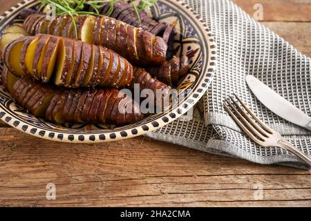 Patate douce - tubercules de potatos doux cuits dans une casserole.Frits et cuits avec des épices et du sel.Couper en morceaux et en tranches.Nourriture saine vue rapprochée.Repas de pommes de terre dans une assiette sur une table en bois.Fourche et couteau. Banque D'Images