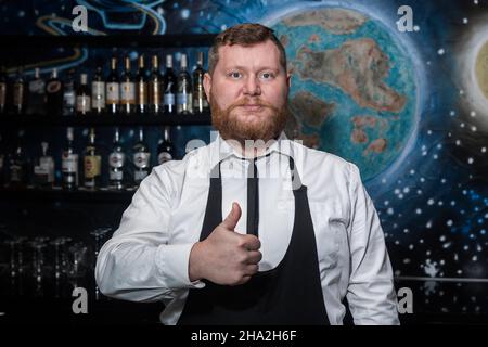Homme barbu adulte d'apparence européenne barman professionnel montre main gestuelle classe cool. Banque D'Images