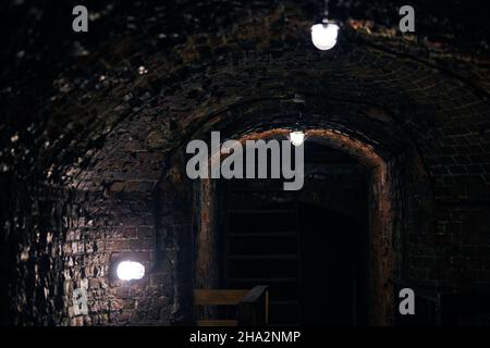 Vieux mur de loft en brique dans le sous-sol militaire secret.Ancienne cave à vin, passage de manoir.Ancien fort allemand d'époque avec éclairage tamisé et murs de briques, Banque D'Images