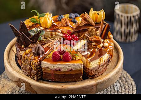 Différentes tranches de divers gâteaux, faisant une seule tarte entière sur le support à gâteau Banque D'Images
