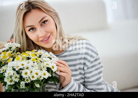 Femelle posant avec un bouquet de fleurs à la maison.Femme au foyer a reçu un cadeau pour les vacances.Anti-allergie.Belle-belle belle blonde dame est détendue, profiter Banque D'Images